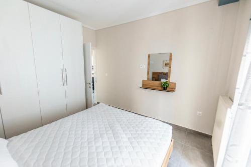 ein weißes Schlafzimmer mit einem Bett und einem Spiegel in der Unterkunft Stylish Urban Getaway by thesbnb in Thessaloniki