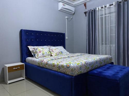 a blue bed with a blue headboard and a window at CASILINA GUEST HOME in Limbe