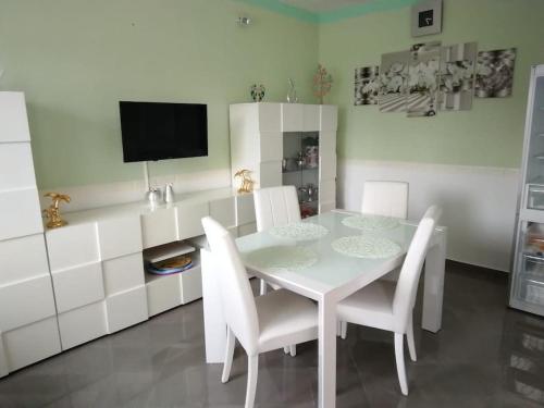 uma sala de jantar branca com uma mesa e cadeiras brancas em Casa Falconara em Noto Marina