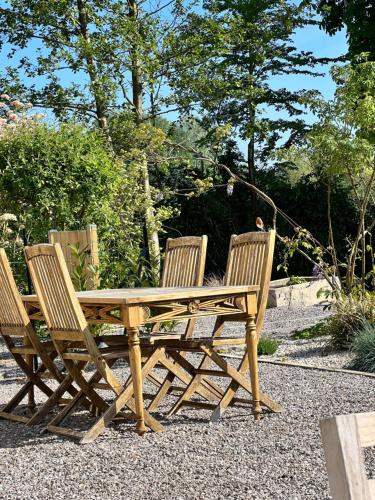 a wooden table and two chairs around a wooden bench at Manoir Les Feuillantines Piscine & Spa in Isques