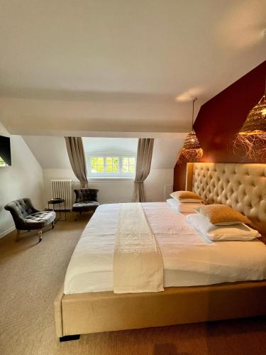 a bedroom with a large bed and a chair at Manoir Les Feuillantines Piscine & Spa in Isques