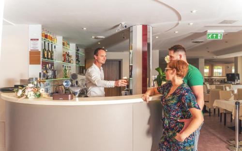 Un gruppo di persone che si trovano al bancone di un bar di Granada Conference, Wellness and Sport Hotel a Kecskemét