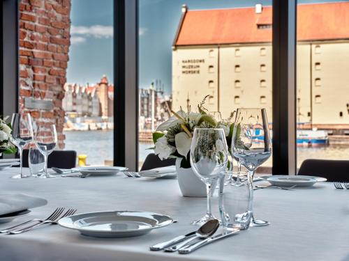 a table with glasses and plates and a view of the city at Holiday Inn Gdansk - City Centre by IHG in Gdańsk