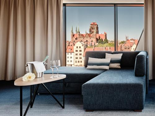 a living room with a couch and a large window at Holiday Inn Gdansk - City Centre by IHG in Gdańsk