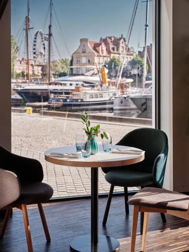 a table and chairs with a view of a marina at Holiday Inn Gdansk - City Centre by IHG in Gdańsk