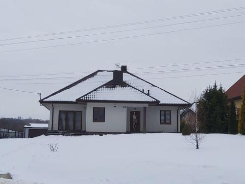 a house with snow on the ground in front of it at Green Hill House in Pępice