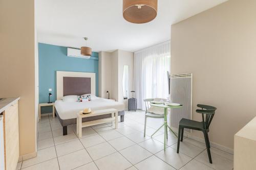 1 dormitorio con 1 cama, mesa y sillas en Appart'City Classic Bordeaux Aéroport St Jean D'Illac en Saint-Jean-dʼIllac