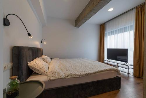 Schlafzimmer mit einem Bett mit einem Tisch und einem TV in der Unterkunft Fabrica Apartments 13 in Cluj-Napoca