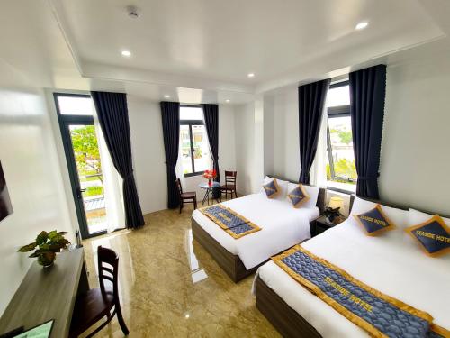 a hotel room with two beds and a desk at Seaside Hotel - Rach Gia in Rạch Giá