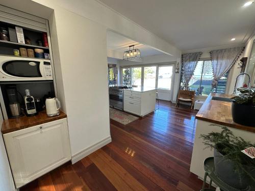 an open kitchen and living room with wooden floors at Bells Beach Bungalow in Clontarf