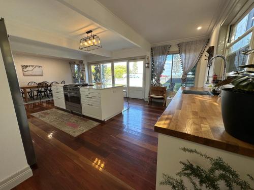 Bells Beach Bungalow في Clontarf: مطبخ وغرفة معيشة مع أرضيات ونوافذ خشبية