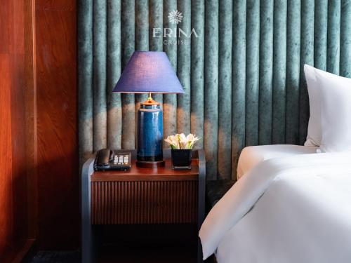 a lamp on a table next to a bed at Erina Cruise by HAG in Ha Long
