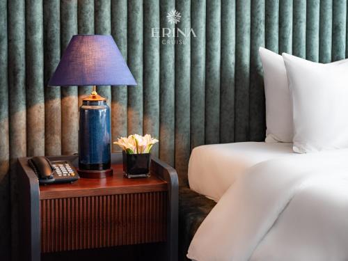 a lamp on a table next to a bed at Erina Cruise by HAG in Ha Long