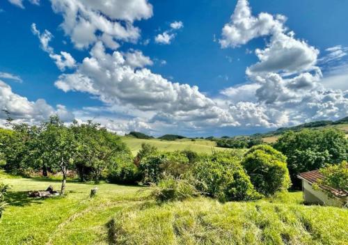 a field with trees and a blue sky with clouds at Residence La Borde in Plavilla
