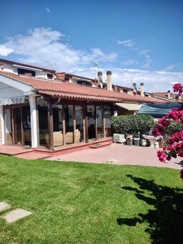 a house with a patio and a yard with pink flowers at Villa Mery in LʼAmericano