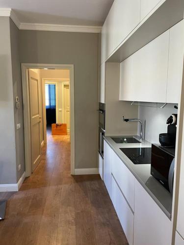 a kitchen with white cabinets and a wooden floor at CARDUCCI 3 in Forte dei Marmi