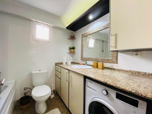 La salle de bains est pourvue de toilettes, d'un lavabo et d'un lave-linge. dans l'établissement KUŞADASI MERKEZDE 3+1 DENİZ MANZARALI KONSEPT DAİRE, à Kusadası