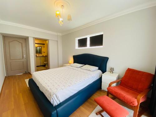 - une chambre avec un lit bleu et une chaise rouge dans l'établissement KUŞADASI MERKEZDE 3+1 DENİZ MANZARALI KONSEPT DAİRE, à Kusadası