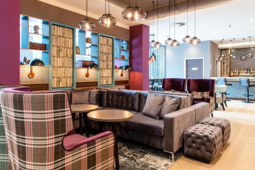 a living room with a couch and tables and a bar at Premier Inn Leipzig City Oper in Leipzig