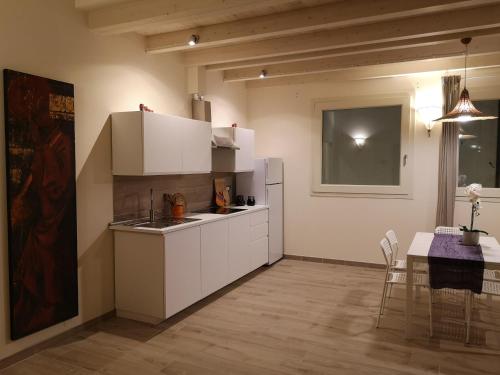 een keuken met witte kasten en een eettafel bij Da Cinema a Residenza d'Artista BLUE YELLOW RED in Orbetello