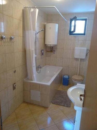 a bathroom with a tub and a toilet at Apartman Vidaković in Bilje