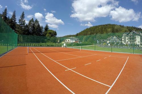 an orange tennis court with houses in the background at Hotel Zimnik Luksus Natury Spa & Wellness in Szczyrk