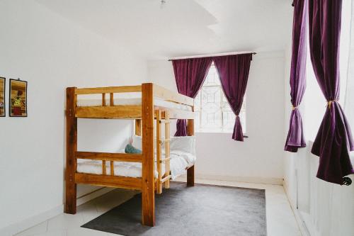 - une chambre avec des lits superposés et des rideaux violets dans l'établissement Karibu Africa Home, à Moshi