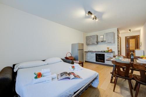 a bedroom with a large white bed and a kitchen at Studio Genzianella Ski In-Ski Out 100m - Happy Rentals in Sestriere