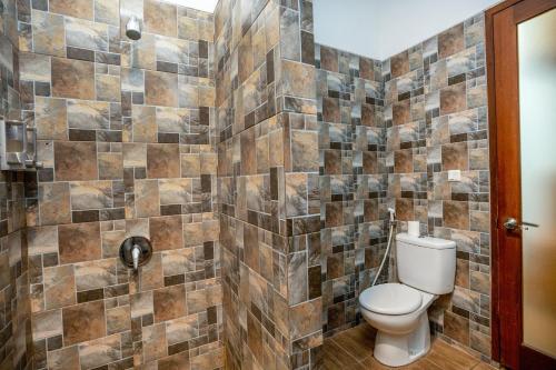 a bathroom with a toilet and a tiled wall at Sedasa Lodge in Canggu