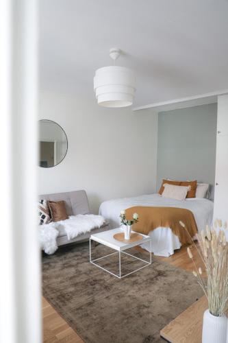 a white living room with a bed and a table at Studio-Joki - Valoisa asunto keskustassa in Turku
