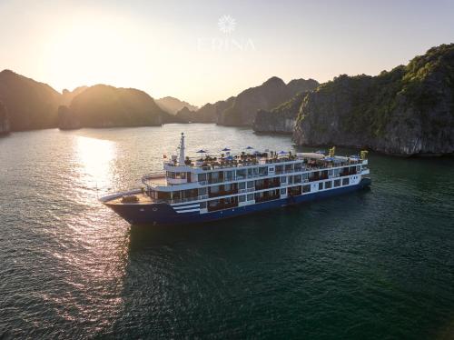 a cruise ship in the water near some cliffs at Erina Cruise by HAG in Ha Long