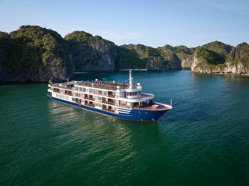a cruise ship in the water near some cliffs at Erina Cruise by HAG in Ha Long