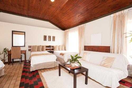 sala de estar con 2 camas y sofá en Touraco Guesthouse, en Pretoria