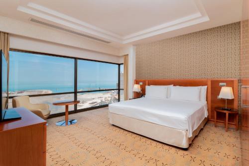 a hotel room with a bed and a large window at Holiday Inn Kuwait by IHG in Kuwait