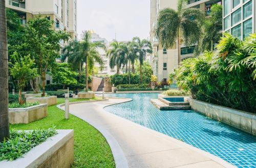 a swimming pool in a city with palm trees and buildings at Rama9 Luxe Suites in Bangkok