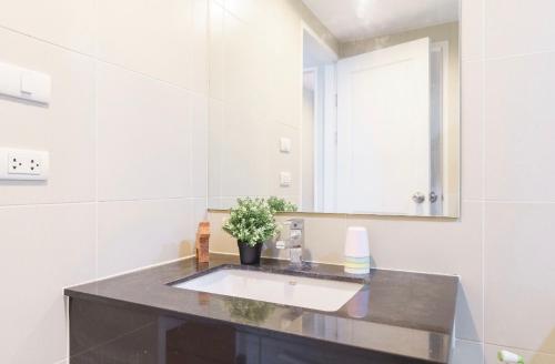 ein Bad mit einem Waschbecken und einem Spiegel in der Unterkunft Belle Rama9 精品公寓 in Bangkok