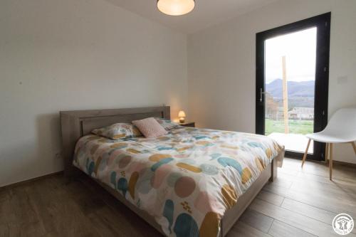 a bedroom with a bed and a large window at Villa jacuzzi, terrain de pétanque et aire de jeux vue sur les Pyrénées in Seilhan