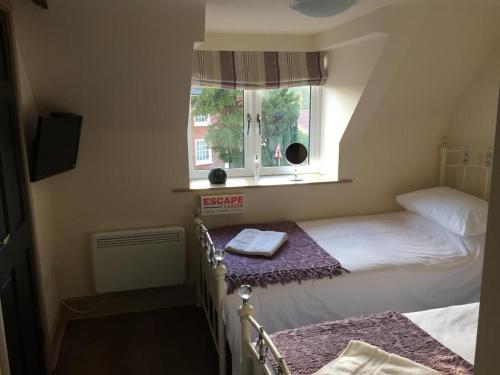 1 dormitorio con 2 camas y ventana en The Crown Inn Smallburgh, en Smallburgh