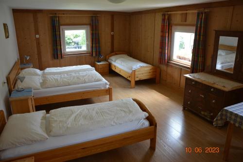 a room with three beds and a dresser and two windows at Villa Vidal in Villabassa