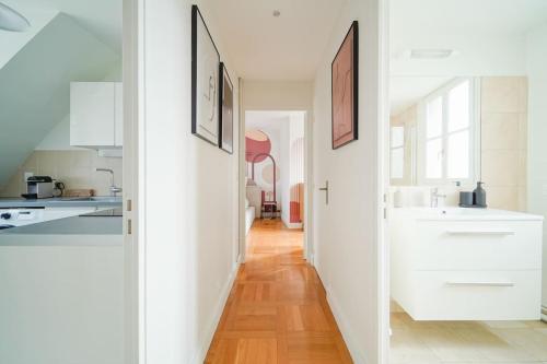 un couloir menant à une cuisine avec des placards blancs dans l'établissement Appartement Haussmannien 16ème arrondissement, à Paris