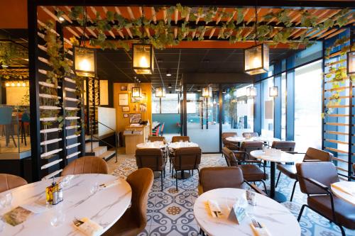 a restaurant with white tables and chairs and windows at ibis budget Besançon Centre Gare in Besançon