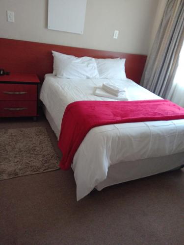 Thokoza guest house في منزيني: غرفة نوم مع سرير مع اللوح الأمامي الأحمر
