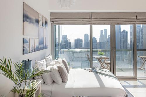 a bedroom with a white bed and a large window at Nasma Luxury Stays - Charming And Fancy Studio In The Heart of Dubai in Dubai