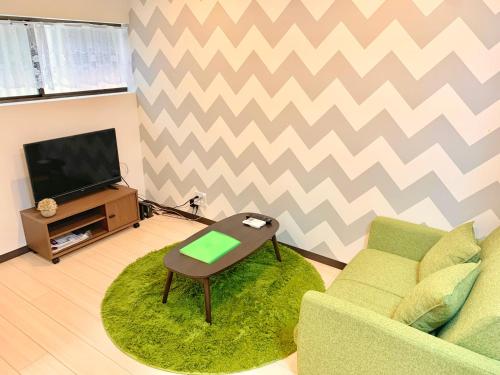 a living room with a green couch and a television at ＊大阪＊一棟貸切、駅から徒歩3分、複数駅利用可、電車で梅田まで5分、地下鉄でなんばまで9分 in Osaka