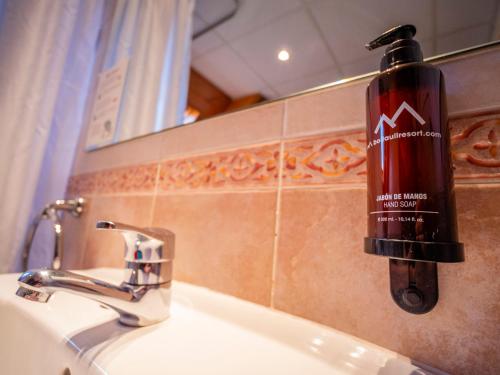 eine Mundwasser-Flasche an der Wand eines Badezimmerswaschbecken in der Unterkunft Hotel Romànic in Pla de l'Ermita