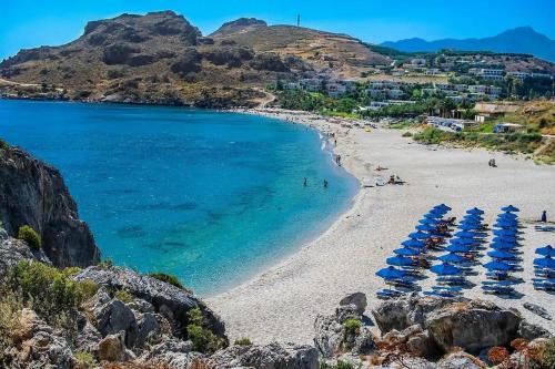 una spiaggia con ombrelloni blu e l'oceano di Argyro's vintage House a Spílion