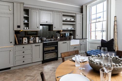 een keuken met witte kasten en een houten tafel bij Malvern - By Luxury Apartments in Cheltenham