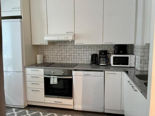 a kitchen with white appliances and white cabinets at Kotimaailma Apartments near center apartment+sauna in Lahti