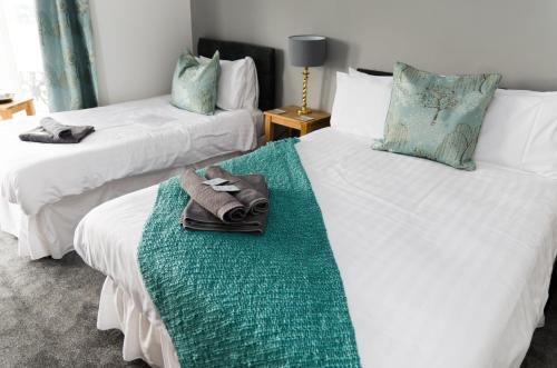 two beds with towels on them in a room at The Lakeside in Redcar