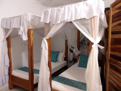 1 Schlafzimmer mit 2 Etagenbetten und weißen Vorhängen in der Unterkunft Pendo Villas Diani Beach in Diani Beach